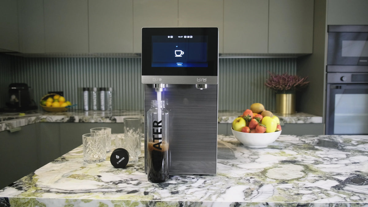 Fontaine à eau de comptoir installée sur un îlot de cuisine moderne, avec un verre placé sous la zone de distribution