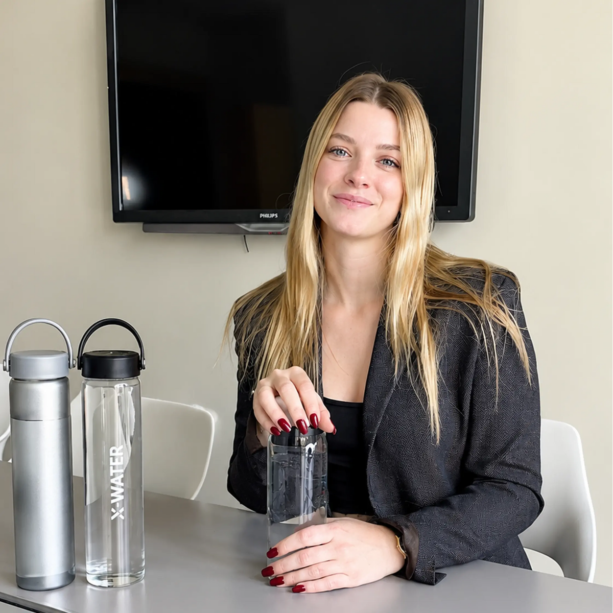 Collaboratrice au bureau avec une bouteille en verre X-Water Image